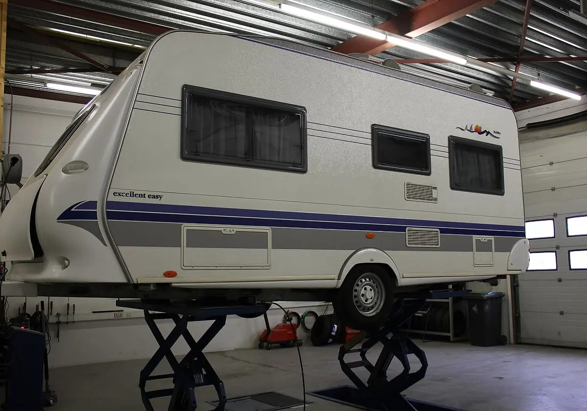 Zijaanzicht van een caravan op de hefbrug in de werkplaats van Twenteland Caravans in Hengelo